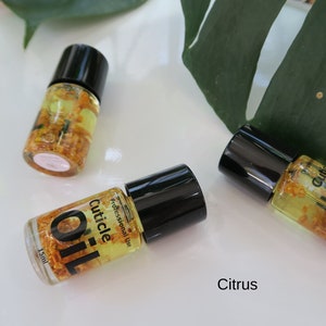 May include: Three small bottles of cuticle oil with black caps and clear glass bottles filled with a yellow liquid and small yellow flower petals. The bottles are labeled "Cuticle Oil" and "Professional Use". The text "Citrus" is written below the bottles.
