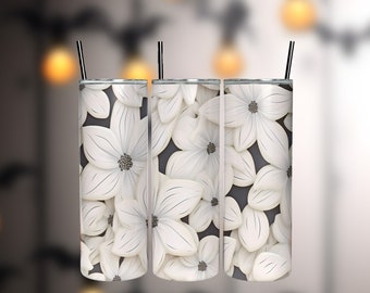 May include: Three stainless steel tumblers with a white floral design against a dark gray background. Each tumbler has a black straw. The floral pattern features large, stylized white flowers with dark centers.