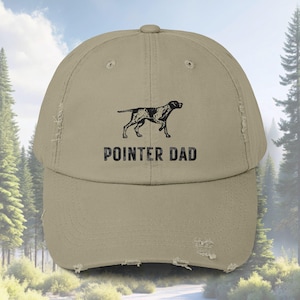 May include: A beige distressed baseball cap with a black and white illustration of a German Shorthaired Pointer dog and the text "POINTER DAD".