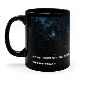 Op de afbeelding: Zwarte koffiemok met een galaxy print en de quote "Stuff keeps getting older" - Graham Hancock.