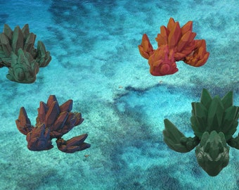 Può includere: Quattro figurine a forma di cristallo in diversi colori, tra cui verde e rosso, galleggiano su uno sfondo di acqua blu.