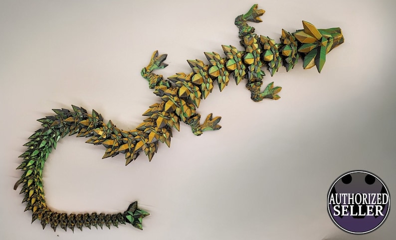 May include: A green and gold origami dragon sculpture. The dragon is made of paper and has a long, serpentine body with a pointed head and tail.
