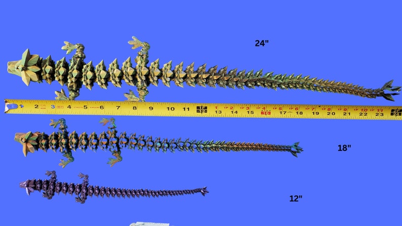 May include: Three origami lizards of different sizes, measuring 12 inches, 18 inches, and 24 inches. The lizards are made of paper and have a green, gold, and purple color scheme.
