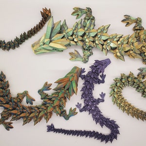May include: Five origami dragons made of paper with iridescent scales in shades of green, gold, and purple. The dragons are arranged in a decorative display.