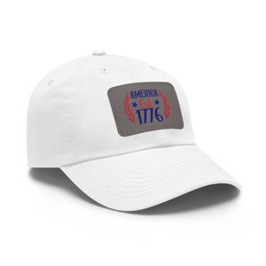 May include: White cotton baseball cap with a gray patch that says "AMERICA Est. 1776" in blue and red lettering with a laurel wreath around the text.