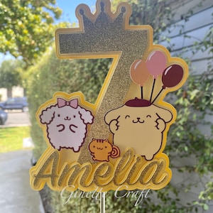 May include: A yellow cake topper with a glitter number 7, a crown, two cartoon dogs, a cat, and balloons. The name Amelia is written in gold glitter below the number. The text "Ginett Craft" is written below the name.