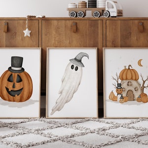 Pode incluir: Três impressões emolduradas com tema de Halloween com ilustrações em aquarela. A primeira impressão apresenta uma abóbora com um chapéu de cartola, a segunda impressão apresenta um fantasma branco e a terceira impressão apresenta uma casa de abóbora com uma lua e estrelas.