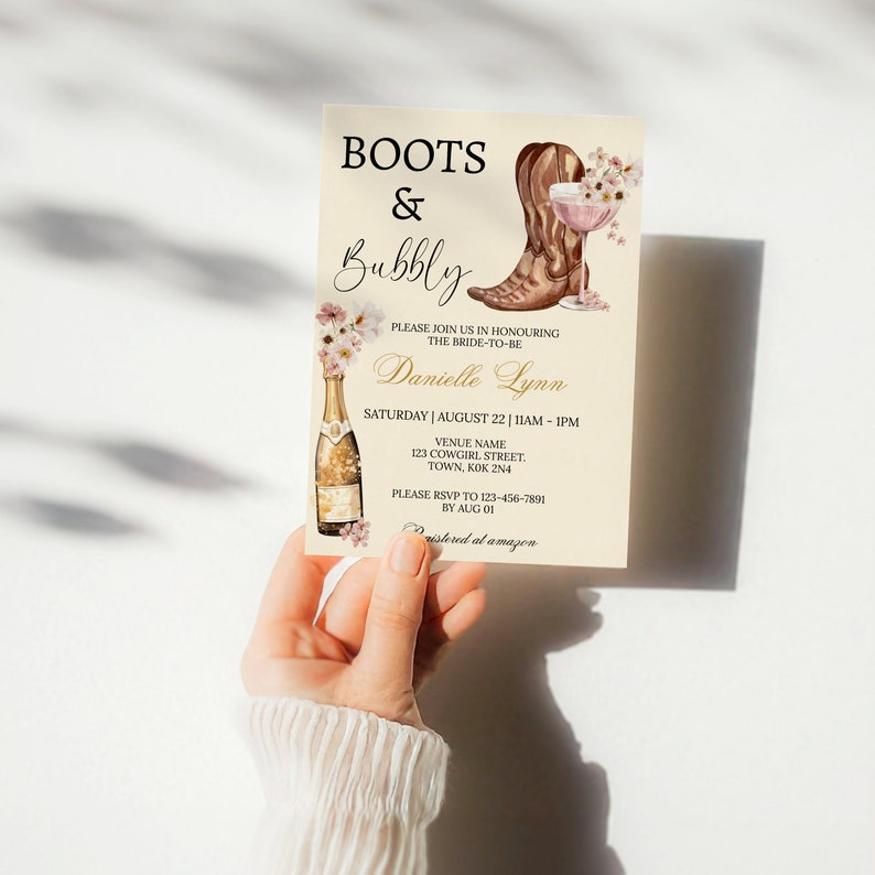 May include: A beige bridal shower invitation with a watercolor illustration of a champagne bottle, a glass of champagne, and a brown cowboy boot. The text on the invitation reads "Boots & Bubbly" and "Please join us in honouring the bride-to-be Danielle Lynn".