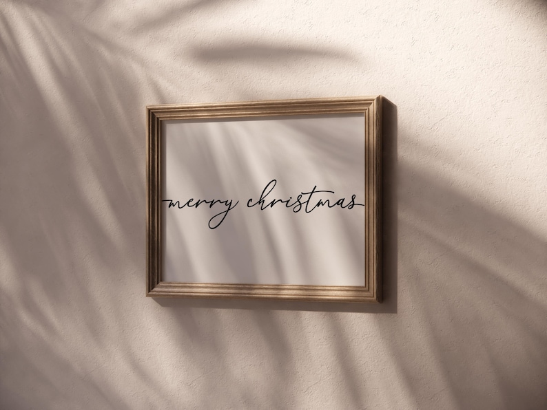 May include: A gold-framed picture with a white background and the text "merry christmas" written in black cursive.