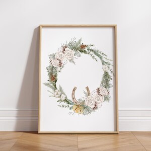 May include: A framed watercolor painting of a winter wreath with white flowers, pine branches, cotton bolls, and a horseshoe.
