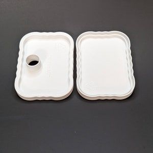 May include: Two white plastic trays with scalloped edges. One tray has a round hole in the center.