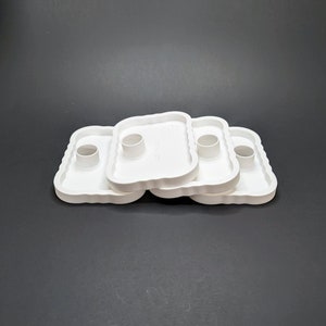 May include: Three white plastic cake decorating tips with scalloped edges and a center hole. The tips are stacked on top of each other.