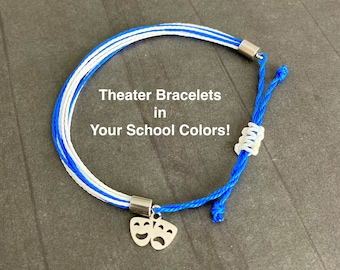 May include: A blue, white, and silver theater bracelet with a charm featuring comedy and tragedy masks. The bracelet has the text "Theater Bracelets in Your School Colors!"