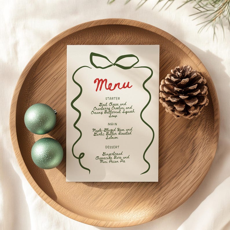 May include: A festive menu card with a green bow design and red text that reads "Menu." The menu includes starter, main, and dessert options. The card is on a wooden tray with ornaments and a pinecone.