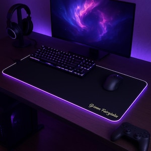 May include: A black gaming mousepad with a purple glow around the edges. The mousepad has the text "Grimm Fairytales" printed in gold lettering. A black gaming mouse is on the mousepad.