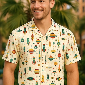 Könnte beinhalten: Ein kurzärmeliges Hemd mit Knöpfen und einem Retro-Druck von Raketen, Raumschiffen, Planeten und Sternen auf cremefarbenem Hintergrund.
