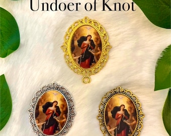 May include: Three oval-shaped charms featuring a religious image of the Virgin Mary, known as the "Undoer of Knots". The charms are in gold and silver tones with intricate details. The image depicts Mary holding a rope with knots, symbolizing the undoing of life's challenges.