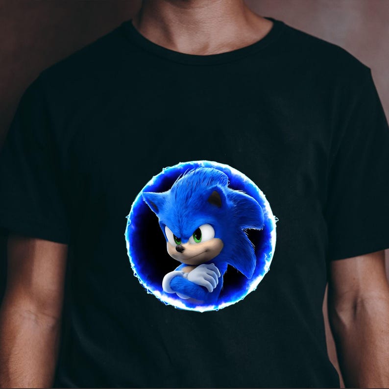 May include: Black t-shirt featuring a blue cartoon character, Sonic the Hedgehog, within a blue glowing circle. The character has blue fur, green eyes, and crossed arms. The shirt is a solid color.