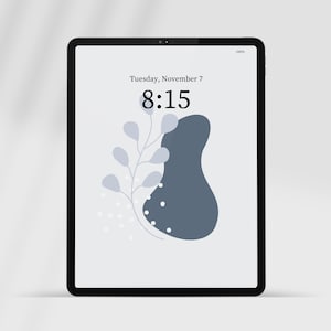 Könnte beinhalten: Ein Tablet-Bildschirm zeigt eine digitale Uhr mit der Zeit 8:15, dem Datum Dienstag, 7. November, und ein einfaches abstraktes Design mit einer blauen Form und einem weißen Zweig mit Blättern.