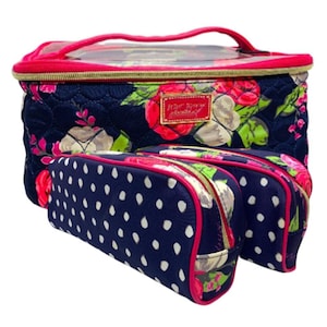 May include: A set of three cosmetic bags. The largest bag is navy blue with a floral pattern and a pink handle. Two smaller bags are navy blue with white polka dots. All bags have pink trim.