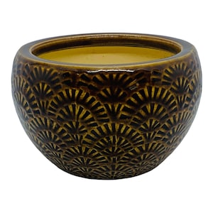May include: A brown ceramic bowl with a textured, fan-like pattern. The bowl has a rounded shape and a smooth, glossy finish. The interior of the bowl is a lighter shade of brown. This decorative bowl is suitable for home decor.