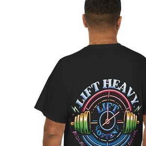 May include: Black t-shirt with a colorful graphic of a weightlifting barbell and clock with the text "Lift Heavy Lift Often Because Progress Never Takes A Day Off."