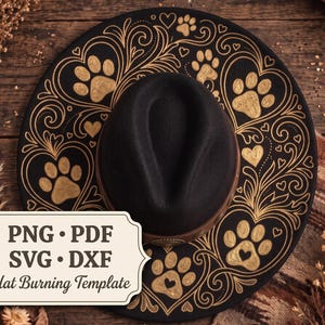 May include: A black hat featuring a gold-colored decorative pattern of swirling filigree, hearts, and paw prints. A white rectangular label with rounded corners displays the text: PNG • PDF SVG • DXF Hat Burning Template.