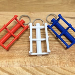 May include: Three keychains with different colored metal frames and a central metal rod. The keychains are red, white, and blue.