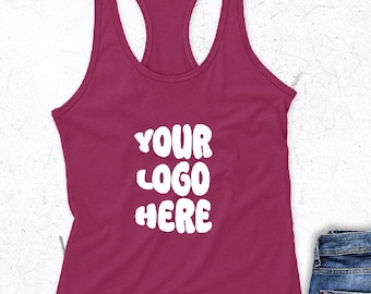 May include: A maroon racerback tank top with the text "YOUR LOGO HERE" in white. The tank top is made of a soft material and has a scoop neck design. Part of a pair of blue jeans is visible in the image.
