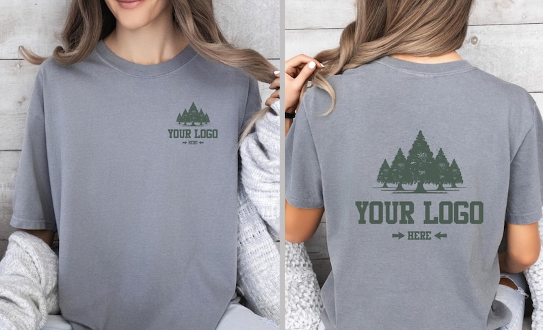 Puede incluir: Camiseta gris de manga corta con un gr&aacute;fico de bosque y el texto "YOUR LOGO" con una flecha. La camiseta est&aacute; hecha de un material suave. El dise&ntilde;o est&aacute; en la parte delantera y trasera de la camiseta.