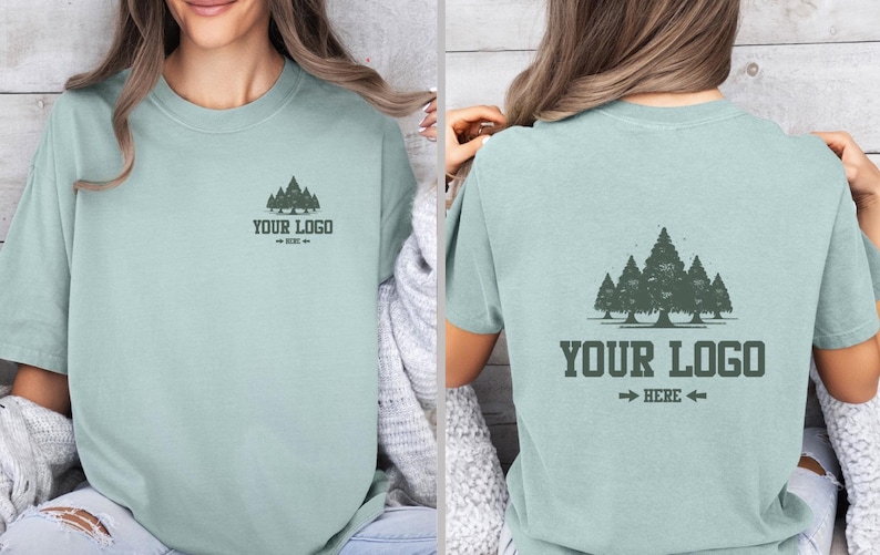Puede incluir: Camiseta verde claro con un dise&ntilde;o de bosque en la parte delantera y trasera. La parte delantera tiene un peque&ntilde;o dise&ntilde;o de bosque y el texto "YOUR LOGO - HERE -". La parte trasera tiene un dise&ntilde;o de bosque m&aacute;s grande y el texto "YOUR LOGO - HERE -".