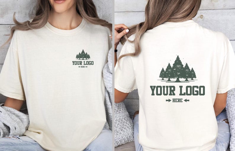 Puede incluir: Camiseta color crema con un gr&aacute;fico de bosque y el texto "YOUR LOGO HERE" en verde oscuro. El dise&ntilde;o se repite en la parte delantera y trasera. La camiseta tiene mangas cortas y un corte holgado.
