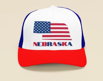 May include: A white, blue, and red trucker hat with the state of Nebraska outlined in the shape of the American flag and the word "NEBRASKA" printed below the flag.