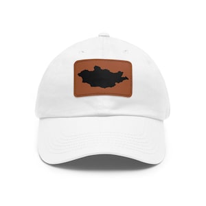 May include: A white baseball cap featuring a rectangular brown patch centered on the front. The patch displays a solid black silhouette of the country of Mongolia. The cap has a curved brim and a structured crown with a button at the top.