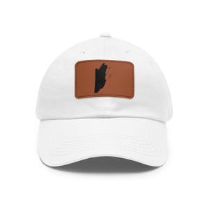 May include: A white baseball cap featuring a rectangular brown leather patch centered on the front. The patch displays a black silhouette of the country of Belize. The cap has a curved brim and a structured crown with a button on the top.