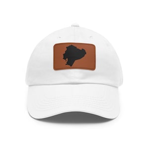 May include: A white baseball cap featuring a rectangular brown patch centered on the front panel. The patch displays a solid black silhouette of the map of Ecuador. The cap has a curved brim and stitched detailing across the crown and visor.