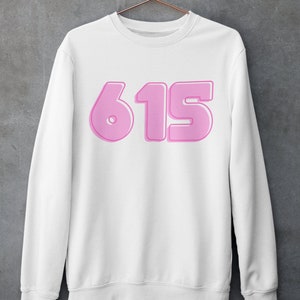 May include: White sweatshirt with a pink 615 graphic on the front.