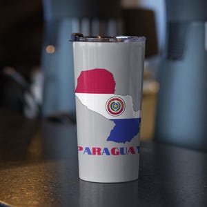 May include: A white travel mug with a gray outline of Paraguay and the Paraguayan flag inside the outline. The word "PARAGUAY" is written in red and blue letters below the outline.