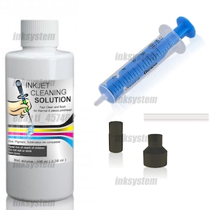 Puede incluir: Una botella blanca de solución de limpieza para inyección de tinta, una jeringa azul y transparente, dos boquillas negras y un tubo blanco. La etiqueta dice "INKJET CLEANING SOLUTION" y "Volumen neto: 100 ml".