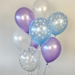 Puede incluir: Un mont&oacute;n de globos en blanco, azul claro y morado con patrones de copos de nieve. Los globos est&aacute;n atados juntos y listos para una fiesta.