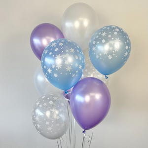 Puede incluir: Un ramo de globos en varios tonos de azul y morado con patrones de copos de nieve. Los globos est&aacute;n atados juntos con una cinta transparente.