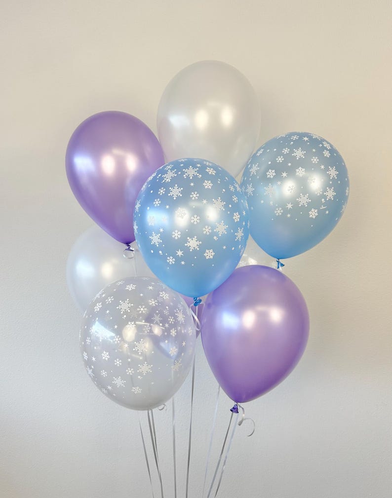 Puede incluir: Un grupo de globos en varios tonos de azul y morado, algunos con un patr&oacute;n de copo de nieve. Los globos est&aacute;n atados juntos y listos para una celebraci&oacute;n.