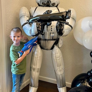 Pu&ograve; includere: Un grande palloncino in alluminio a grandezza naturale a forma di un personaggio Stormtrooper di Star Wars. Il palloncino &egrave; bianco e argento con dettagli neri, raffigurante l'iconico casco e l'armatura. Tiene in mano un fucile blaster giocattolo nero.
