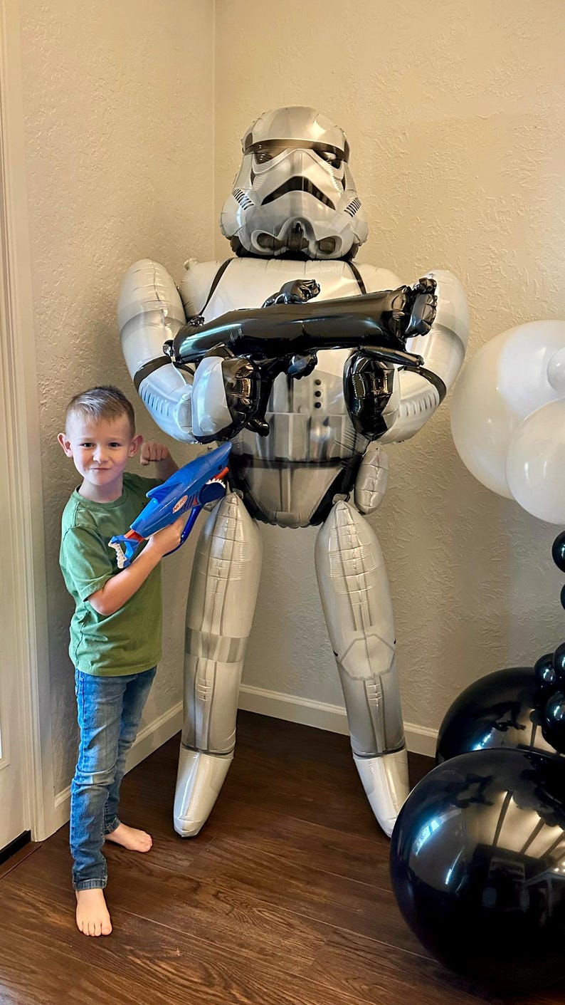 Pu&ograve; includere: Un grande palloncino in alluminio a grandezza naturale a forma di un personaggio Stormtrooper di Star Wars. Il palloncino &egrave; bianco e argento con dettagli neri, raffigurante l'iconico casco e l'armatura. Tiene in mano un fucile blaster giocattolo nero.