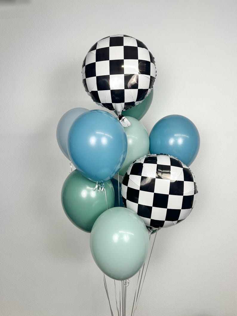 Puede incluir: Un ramo de globos en tonos azules y verdes, con dos globos redondos a cuadros blancos y negros. Los globos est&aacute;n atados con cinta plateada, creando un arreglo festivo.
