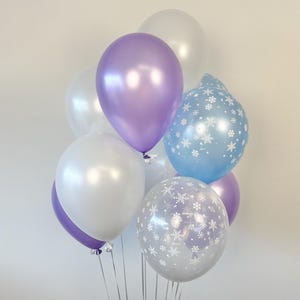 Puede incluir: Un mont&oacute;n de globos en blanco, azul claro y morado. Algunos de los globos tienen un patr&oacute;n de copo de nieve.