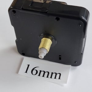 K&ouml;nnte beinhalten: Schwarzes Uhrwerk mit goldfarbenem Schaft und einem wei&szlig;en Etikett mit der Aufschrift "16 mm".