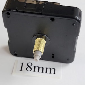 K&ouml;nnte beinhalten: Schwarzes Uhrwerk mit einer goldfarbenen Welle und einer wei&szlig;en Kunststoffspitze. Die Welle ist 18 mm lang.