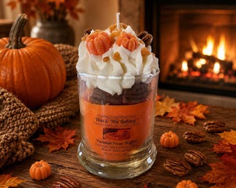 May include: A clear glass candle jar filled with brown wax, topped with white whipped wax and small orange pumpkin-shaped wax pieces. The orange label reads Wax & Wix Bakery, Pumpkin Pecan Waffles, and 340 g. A single white wick is centred on top.