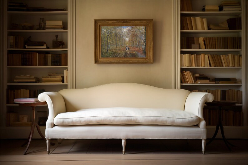 May include: A white sofa with a curved back and wooden legs sits in a room with two white bookshelves filled with books. A framed painting of a forest path hangs on the wall above the sofa.